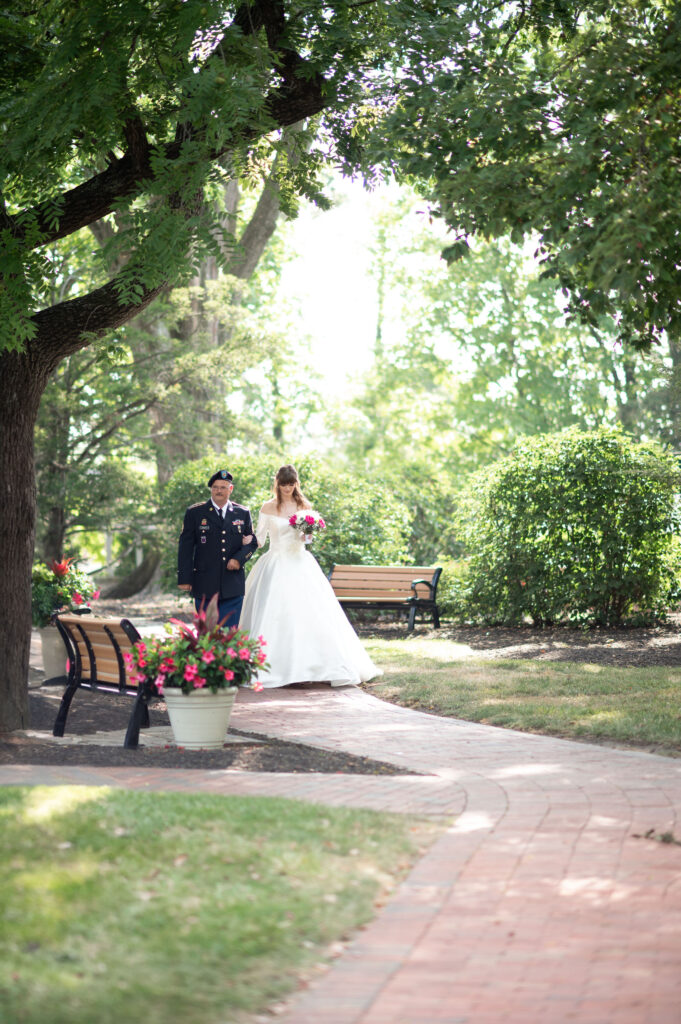 The bride and her dad walk up the aisle together framed by nature in a picturesque setting. 