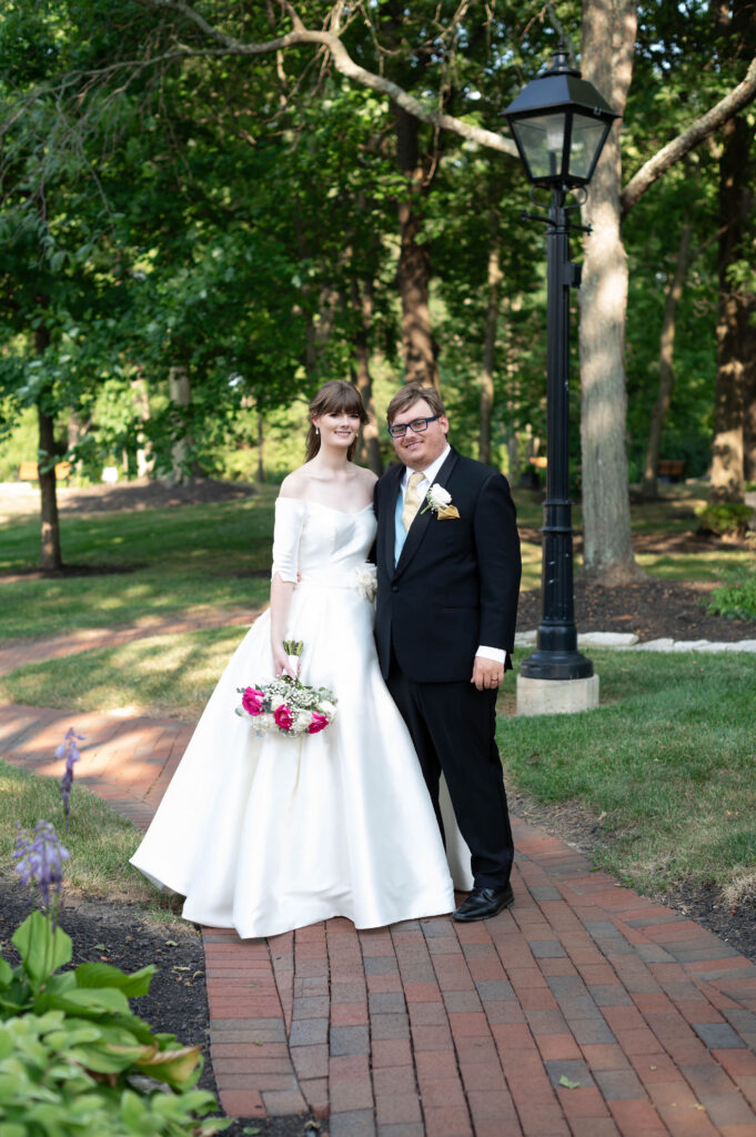 The bride and groom stand alongside one another, looking to the camera for the traditional wedding pose. 