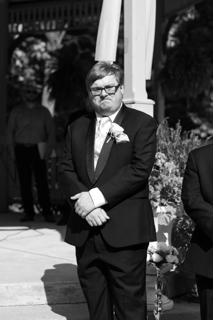 The groom fights back tears as he sees his bride walking towards him for their wedding ceremony. 